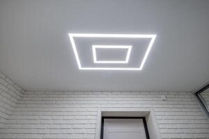 A white brick wall with a square light above it photo