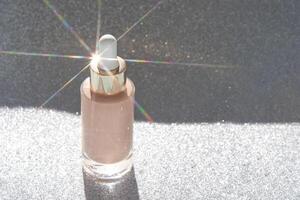 Luminous glass bottle with dropper and glittering background in soft light reflection. photo