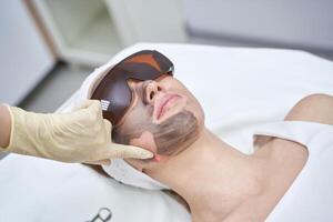 Young caucasian female undergoes laser treatment with protective goggles in spa setting. photo