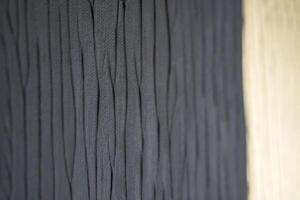 Close up of textured dark fabric with wavy pattern next to wooden surface. photo