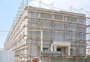 Large concrete building under construction with scaffolding and blue sky in background. photo