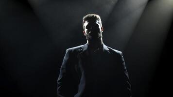 Dark silhouette of bearded man in backlight against black background. Handsome, stylish male posing in a business suit. Copy space for text, banner, ads photo