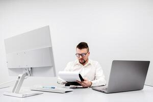 A businessman, financial manager or recruiter, works at a computer in a modern office. The concept is to show the focus and productivity. White background, free copy space photo