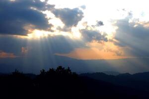 Sun ray of sun light shining down on cloud and sky with silhouette dusk and twilight on the valley mountain photo