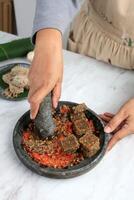 Female hand Crushed ROasted Oncom on the Chilli, Step making Sambal Oncom photo