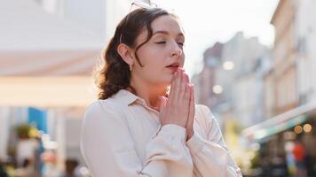 Portrait of woman praying with closed eyes to God asking for blessing, help, forgiveness outdoors video