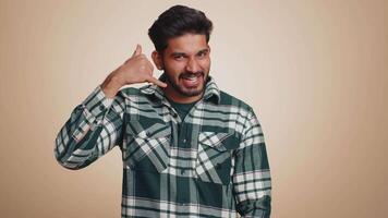 Bearded indian man looking at camera doing phone gesture like says hey you call me back conversation video
