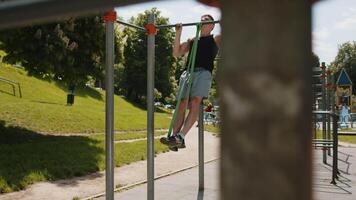 Athletic man in sportswear doing pull-ups exercises on horizontal bar with help of elastic expander video