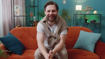 Caucasian man smiling friendly at camera, waving hands gesturing hello, hi, greeting at home on sofa video