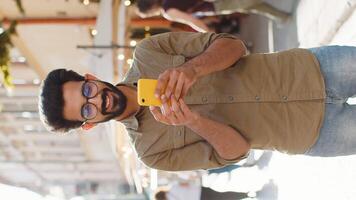 Indian man use smartphone typing text messages browsing internet finishing work chatting online video