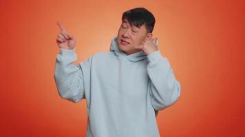 Handsome asian man looking at camera doing phone gesture like says hey you call me back conversation video
