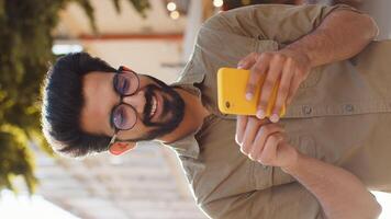 Indian man use smartphone typing text messages browsing internet finishing work chatting online video