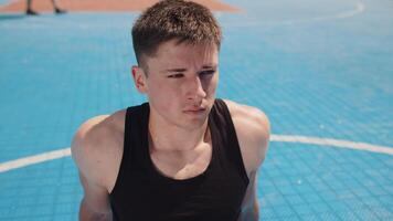 Portrait of tired athletic caucasian man in sportswear relaxing after playing basketball game video