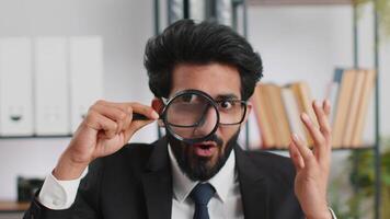 Business man holding magnifying glass near face, looking with big zoomed eye, searching, analysing video