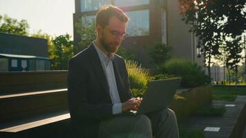 Successful businessman working on steps near office or university use laptop Caucasian business man check email on computer distant work outdoors happy employer in city smiling at camera toothy smile video