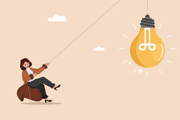 Pulling Towards a Bright Idea A Determined Businesswoman Using a Rope to Draw a Glowing Light Bulb Closer.