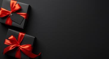 Black gift boxes with red ribbon on black background photo