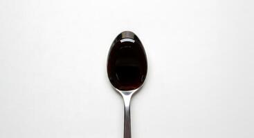 A spoon with a black liquid on it photo