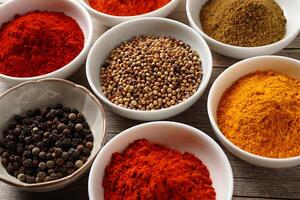 Overhead Close Up of Colorful Aromatic Spices in Ceramic Bowls on Weathered photo