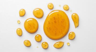 A group of yellow liquid drops on a white surface photo
