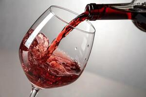 A glass of red wine being poured into it photo