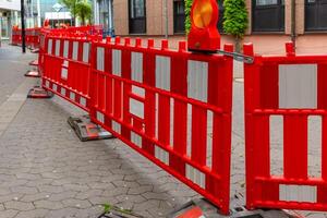 Bright red barriers create a striking contrast against urban architecture during street repairs on a crisp day in a bustling neighborhood photo