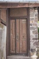 Historic wooden door reveals the charm of ancient architecture in a quaint village nestled among the mountains photo