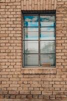 Reflections of clouds shimmer through a window framed by warm, textured brick in a peaceful rural setting during the afternoon photo
