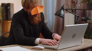 Tired inefficient lazy business man working sleeping on laptop computer with eyes stickers on face video