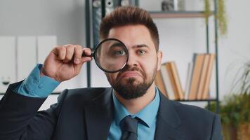 Business man holding magnifying glass near face, looking with big zoomed eye, searching, analysing video