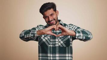 Smiling hindu man makes heart gesture demonstrates love sign expresses good feelings and sympathy video