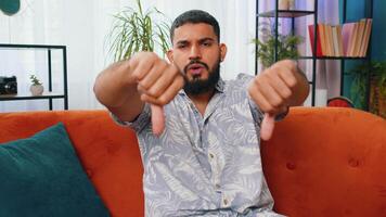 Upset Arabian man showing thumbs down, dislike bad work, disapproval dissatisfied feedback at home video