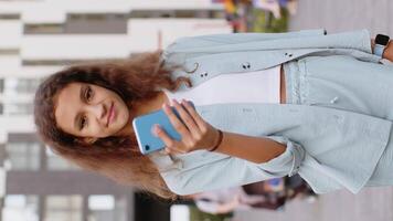 Preteen girl use smartphone typing text messages browsing internet finishing work looking at camera video