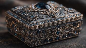 Decorative jewelry box with intricate designs and blue gemstones displayed on dark velvet fabric photo