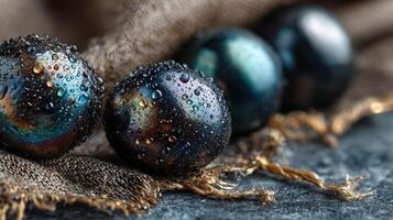 Elegant black and blue polished stones with water droplets on rustic fabric in dim light setting photo
