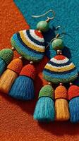 Colorful handcrafted earrings featuring tassels and intricate beadwork on vibrant textile backgrounds photo
