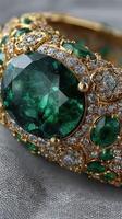 Exquisite gold bracelet with emeralds and diamonds showcased on a soft gray fabric background photo