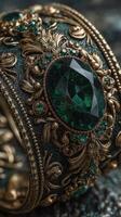 Exquisite vintage bracelet with intricate gold design and large emerald stone displayed on textured dark background photo
