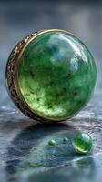 Polished jade stone with intricate gold casing and smaller jade spheres on a reflective surface photo