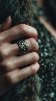 Close-up of a hand adorned with an ornate silver ring on a textured fabric background photo