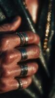 Intricate silver rings adorn fingers against a backdrop of shimmering light during sunset photo