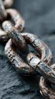 Close-up view of rusty metal chain links against a textured dark surface highlighting wear and age photo