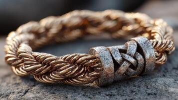 Intricate braided metal bracelet with knot design resting on a textured surface in natural light photo