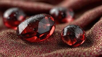 Red glass orbs resting on a textured fabric background with droplets of water glistening in soft light photo