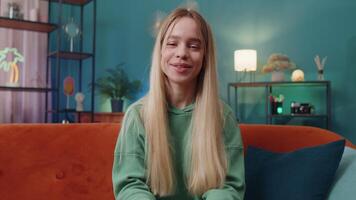 Caucasian woman sitting on home couch, looking at camera, making online webcam conference call video