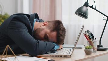 Bored sleepy Caucasian business man worker working on laptop computer, falling asleep at home office video