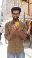 Indian man use smartphone typing text messages browsing internet finishing work chatting online video