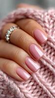 Elegant pink nail polish on well-groomed hand resting on soft knitted fabric in a cozy setting photo