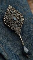 Silver decorative spoon with intricate designs and dark gemstones resting on textured blue fabric photo