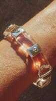 Stylish transparent bracelet glistens under sunlight on a person's wrist outdoors photo